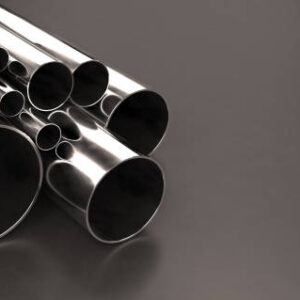 Stack of stainless steel tubes and pipes of various sizes and diameters, with chrome finish, laying on a dark background with copy space on right side. Warehouse samples. Construction industry and metalware. Digitally generated image.